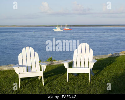 zwei weiße Adirondack Stühle auf Rasen an der Bucht Stockfoto