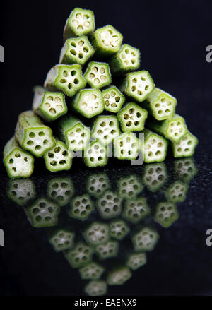 ein Stapel von Okra oder Löffelbiskuits, reflektiert in einem schwarzem Granit-Arbeitsplatte oder Schneidebrett Stockfoto