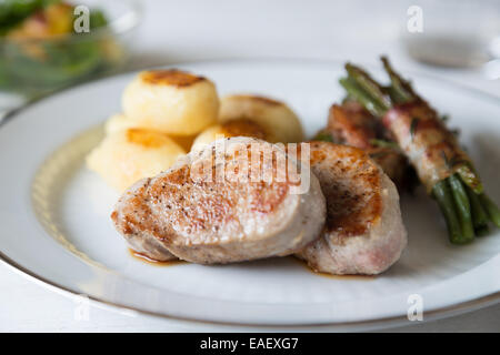 Schweinsmedaillons mit Kartoffeln und Bohnen im Speckmantel Stockfoto