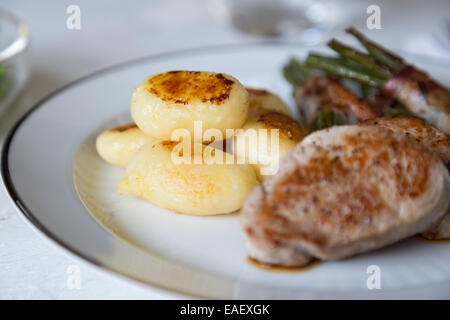 Schweinsmedaillons mit Kartoffeln und Bohnen im Speckmantel Stockfoto