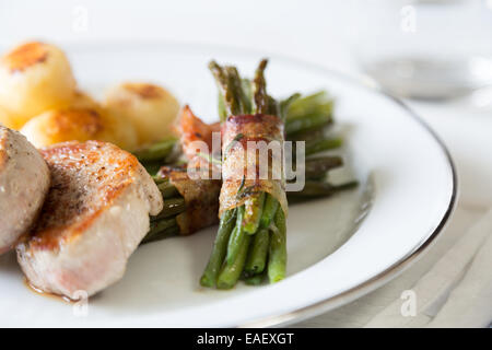 Schweinsmedaillons mit Kartoffeln und Bohnen im Speckmantel Stockfoto