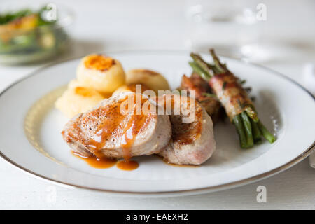 Schweinsmedaillons mit Kartoffeln und Bohnen im Speckmantel Stockfoto