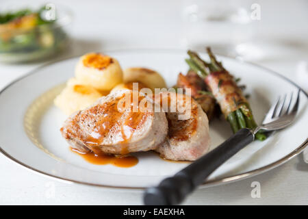 Schweinsmedaillons mit Kartoffeln und Bohnen im Speckmantel Stockfoto