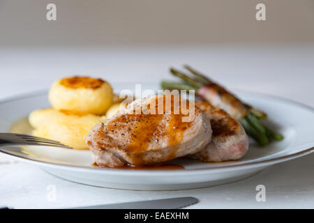 Schweinsmedaillons mit Kartoffeln und Bohnen im Speckmantel Stockfoto