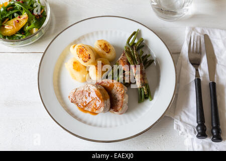 Schweinsmedaillons mit Kartoffeln und Bohnen im Speckmantel Stockfoto