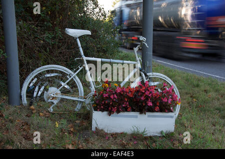 Gefahr. Ein weiß lackiert Ghost Bike und Blumen, die Kennzeichnung der Stelle, wo ein Radfahrer getötet oder bei einem Verkehrsunfall verletzt wurde. Dorset, England Stockfoto