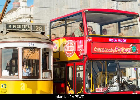 Einer traditionellen gelben Straßenbahn neben einem CitySightSeeing Bus in Lissabon, Portugal. Stockfoto