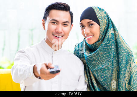 Asiatische muslimischen Mann und Frau vor dem Fernseher im Wohnzimmer Stockfoto