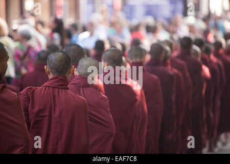 Barfüßige buddhistische Mönche stehen für ihr Mittagessen an, von Gegenständen, die Almosen erhalten, von Almosen, die im Maha Ganayon Kyaung Kloster, Mandalay, geben Stockfoto