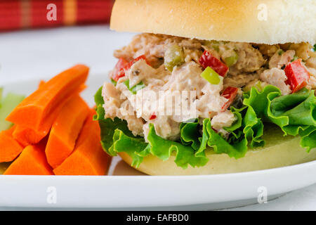 Thunfisch-Salat-Sandwich mit Salat auf einem hausgemachten Brötchen mit gesunden Karotten und Sellerie-Sticks und eine Gurke Stockfoto