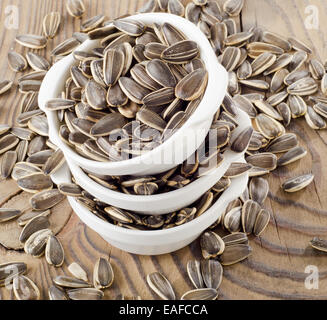 Sonnenblumenkerne in einer weißen Schalen auf einem Holztisch. Selektiven Fokus Stockfoto