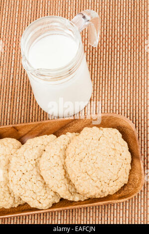 Eine Reihe von frischen, hausgemachten Haferflocken Cookies auf einem Holztablett mit Milch serviert. Stockfoto