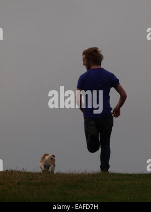 Junge Erwachsene Mann läuft mit seinem Hund, Bude, Cornwall, UK Stockfoto