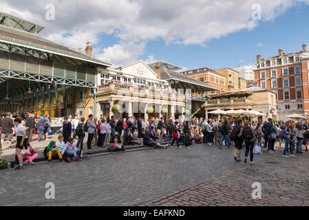 LONDON, Vereinigtes Königreich - 5. Juni 2014: Kundenansturm an einem sonnigen Frühlingstag in Covent Garden als Straßenkünstler in durchführen Stockfoto