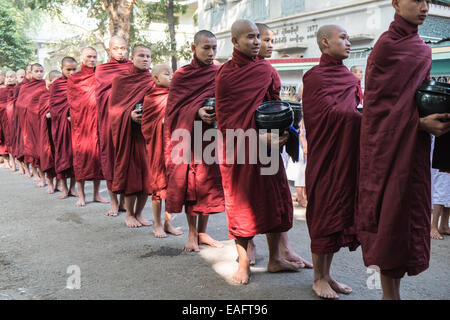 Barfüßige buddhistische Mönche stehen für ihr Mittagessen an, von Gegenständen, die Almosen erhalten, von Almosen, die im Maha Ganayon Kyaung Kloster, Mandalay, geben Stockfoto