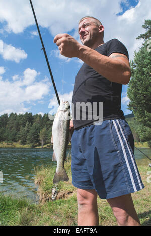 Fischer fing einen Fisch in Berg Damm Stockfoto