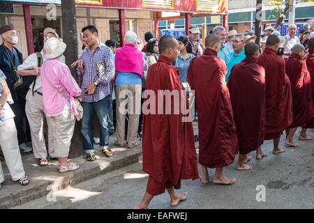 Barfüßige buddhistische Mönche stehen für ihr Mittagessen an, von Gegenständen, die Almosen erhalten, von Almosen, die im Maha Ganayon Kyaung Kloster, Mandalay, geben Stockfoto