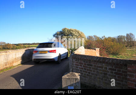 Ein Auto über eine schmale mittelalterliche bucklige Brücke in Wiveton, Norfolk, England, Vereinigtes Königreich. Stockfoto