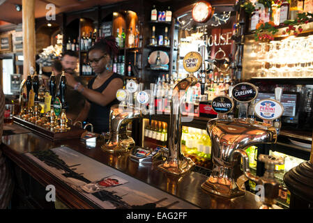 LONDON, Vereinigtes Königreich - 5. Juni 2014: Eine junge Kellnerin serviert Bier in einem Pub in der Nähe von Covent Garden, London Stockfoto