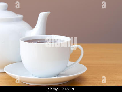 Tasse Tee mit Teekanne auf einem Tisch Stockfoto