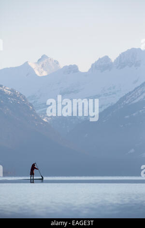 Ein Mann stand Paddel-(SUP) auf einem ruhigen See McDonald in Glacier Nationalpark. Stockfoto