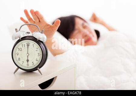 junge Frau, die das Ausschalten der Wecker auf dem Bett Stockfoto