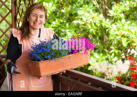 eine reife Frau, so dass einige Gartenarbeit auf einem Balkon Stockfoto