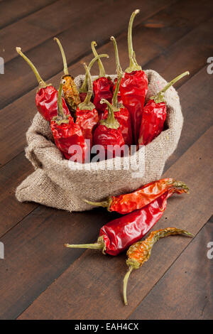 rote Chilischoten in meschotschek Leinwand auf Holztisch Stockfoto