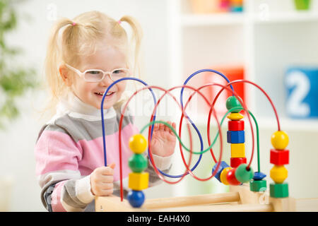 Kid im Eyeglases spielen bunte Spielzeug in Wohngebäude Stockfoto