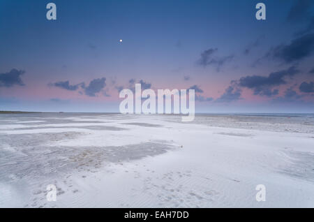 Vollmond und Sonnenaufgang Himmel über Sandstrand an der Nordsee Stockfoto