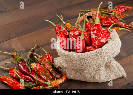 rote Chilischoten in meschotschek Leinwand auf Holztisch Stockfoto