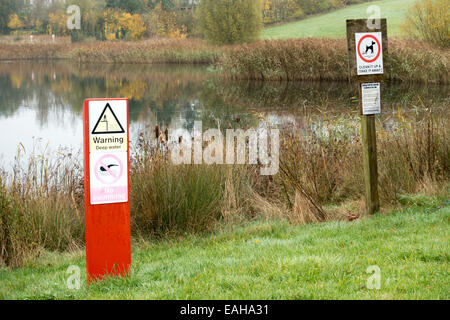 Warnung Tiefenwasser, kein Schwimmen und Hund fouling Strafe Hinweis Schilder am Allenvale See in Hampton Vale, Peterborough, England Stockfoto