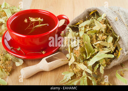 Linden Tee und Blumen in Leinentasche auf Holztisch Stockfoto