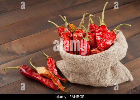 rote Chilischoten in meschotschek Leinwand auf Holztisch Stockfoto