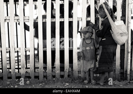 Ein Lao Großmutter und Enkel eine Aufführung durch einen Zaun Stockfoto