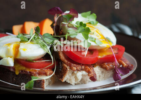 Bunte offen konfrontiert Frühstücks-Sandwich mit Speck, Tomaten, Spiegelei und Sprossen auf frischem Landbrot Stockfoto