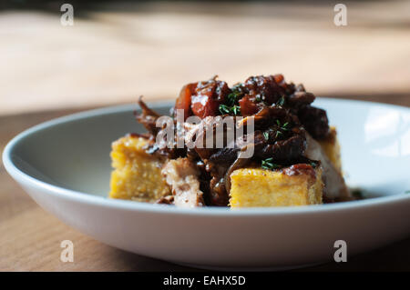 Polenta mit Balsamico geschmortes Huhn mit leckeren saisonalen sautierten greens Stockfoto