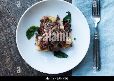 Polenta mit Balsamico geschmortes Huhn mit leckeren saisonalen sautierten greens Stockfoto