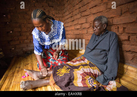 Eine Frau sorgt für einen älteren kranken Patienten zu Hause in Mulanje Bezirk, Malawi. Stockfoto