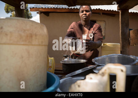 Eine Frau trocknet Gerichte auf einem Teller Wäscheständer vor ihrem Haus in Ndishania Dorf, Bukwo District, Uganda. Stockfoto