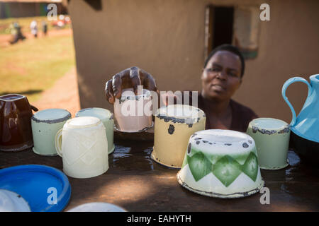 Eine Frau trocknet Gerichte auf einem Teller Wäscheständer vor ihrem Haus in Ndishania Dorf, Bukwo District, Uganda. Stockfoto