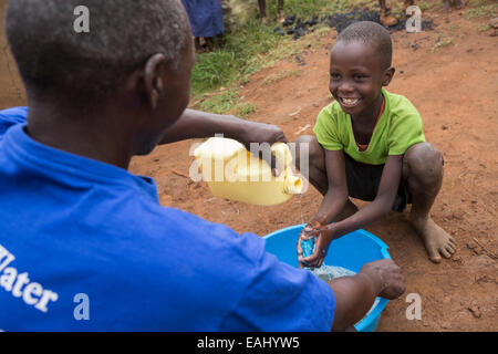 Ein Junge wäscht seine Hände mit Hilfe von einer Gemeinschaft Arbeiter - Bukwo District, Uganda, Ostafrika. Stockfoto