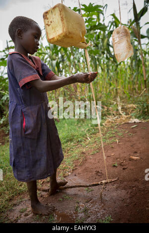 Ein junges Mädchen wäscht ihre Hände mit einem tippy-Hahn in Bukwo District, Uganda, Ostafrika. Stockfoto