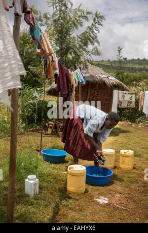 Eine Frau wäscht und trocknet Kleidung auf ihrem Hof im Bukwo District, Uganda. Stockfoto