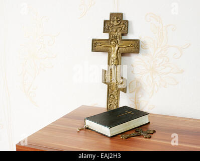 abgenutzte Bibel mit zwei Bronze Kreuze auf dem Holztisch Stockfoto