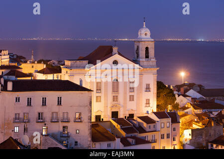 Santo Estevao Kirche nachts im alten Alfama Viertel von Lissabon in Portugal, Tejo im Hintergrund. Stockfoto