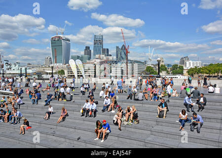 Southwark Büroangestellte und Touristen, die eine heiße, sonnige Mittagspause einlegen Im More London Scoop Amphitheater am Flussufer mit City of London Skyline England Großbritannien Stockfoto