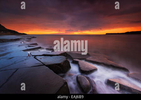 Sonnenuntergang auf der wunderschönen Dorset Küste leuchtenden glänzende Felsen mit Orangen und gelben highlights Stockfoto