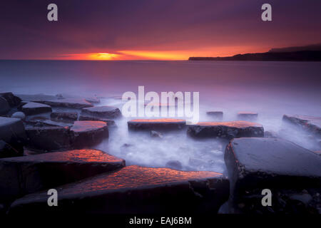 Sonnenuntergang auf der wunderschönen Dorset Küste leuchtenden glänzende Felsen mit Orangen und gelben highlights Stockfoto