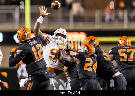 15. November 2104: Oklahoma State Cowboys Quarterback Daxx Garman (12) bekommt einen Pass entfernt unter Druck von Texas Longhorns defensive Tackle Malcom Brown (90) während der NCAA Fußball-das Spiel zwischen der Oklahoma State Cowboys und die Texas Longhorns im Boone Pickens Stadium in Stillwater, OK. Die Longhorns besiegte die Cowboys 28-7. Stockfoto